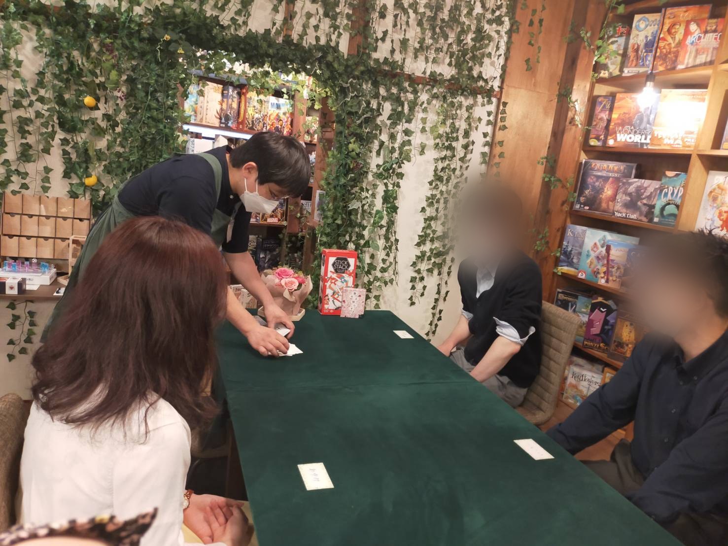 ボードゲームハウスとまり木の店内。緑のテーブルとゲーム棚